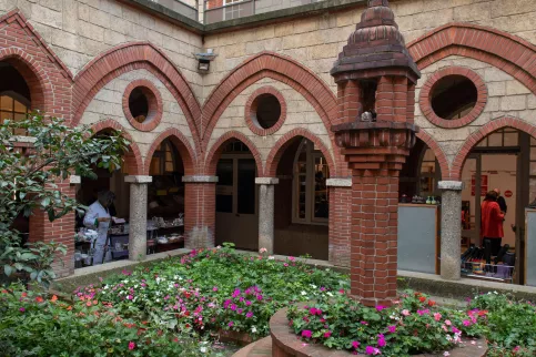 un bâtiment en pierre et brique avec des arches et un petit terrain