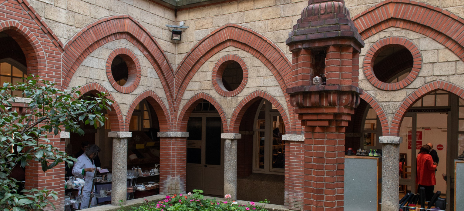 un bâtiment en pierre et brique avec des arches et un petit terrain