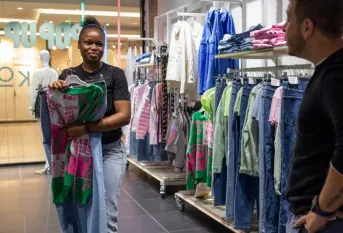 une jeune dans une boutique de vêtements conseillant un client