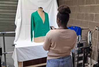 une jeune qui prend un vêtement en photo