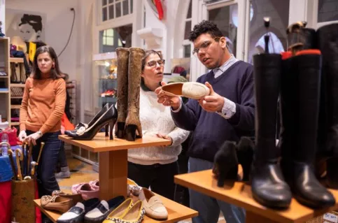 jeune en train de conseiller une cliente dans une boutique de maroquinerie