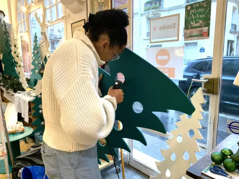 Une jeune qui installe la vitrine de Noël