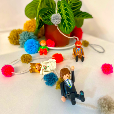 une guirlande avec des pompons et des playmobil